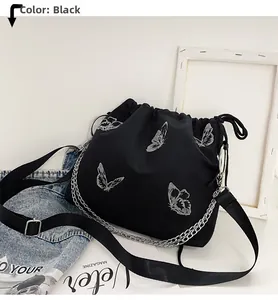 Close-up of black drawstring bucket bag with silver butterfly prints and metal chain