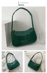 Detail of green crocodile embossed shoulder bag with high gloss finish and gold zipper