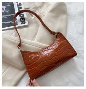 Detalle de textura de cocodrilo marrón en el bolso de hombro elegante con cremallera dorada