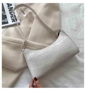 Detalle del bolso baguette blanco con grabado de cocodrilo, cremallera dorada y correa
