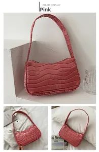 Close-up of pink crocodile embossed pattern and top zipper on small shoulder bag