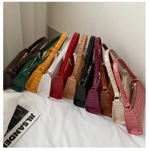 Selección de bolsos baguette con diseño de cocodrilo en once colores sobre tela blanca