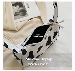 Detail showing the cow print shoulder bag interior with a sturdy zipper and main pocket