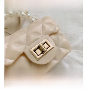 Detail of glossy quilted jelly bag with golden lock and white pearl handle