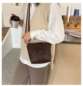 Detail of vintage brown bucket bag with embossed cartoon patterns and wide canvas strap