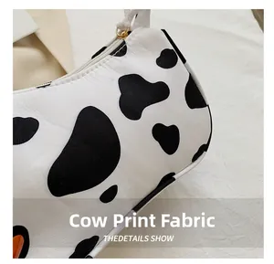 Detail of canvas tote bag featuring classic cow print fabric and golden zipper closure