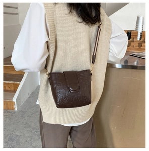 Detail of dark brown vintage bucket bag with embossed star patterns and wide strap