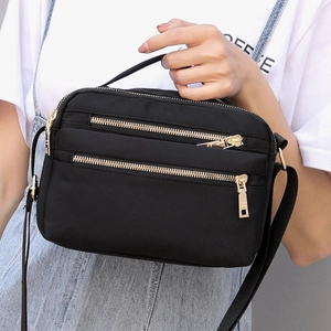 Detail of waterproof black nylon bag featuring gold zippers and sturdy handles