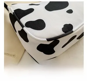 Close-up detail of fine stitching on cow print tote bag with black and white texture