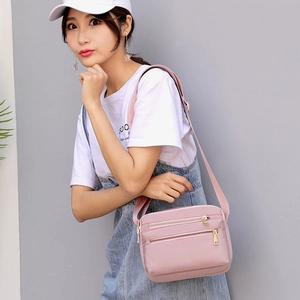 Pink waterproof nylon crossbody bag with multi-layer zippers and gold metal details