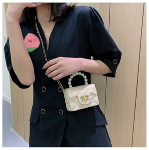 Detail of mini cream crossbody bag with quilted pattern, pearl handle and gold chain