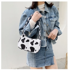 Detailed close-up of a stylish white faux leather tote bag with a black cow print pattern