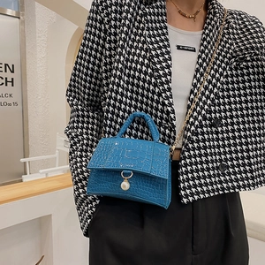 Blue mini handbag with crocodile pattern and pearl charm on houndstooth suit model