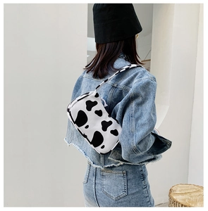 Detail of cow print shoulder bag showing classic black and white canvas pattern on a model
