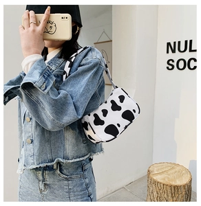 Detail view of stylish cow print shoulder bag worn by model in vintage denim jacket