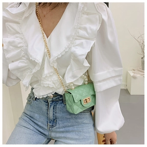 Macro detail of mint green quilted leather bag with pearl handle and golden metal chain