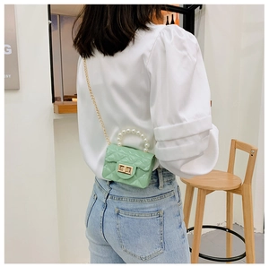 Mint green mini crossbody bag with pearl handle and chain strap on a model