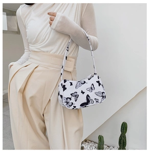 Close-up of a white tote bag featuring black butterfly patterns and slim shoulder straps