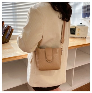 Detail of beige bucket bag featuring embossed star and moon patterns with a wide strap