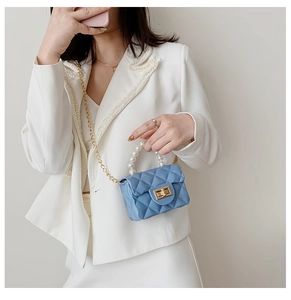 Close-up of sky blue quilted mini handbag with pearl handle and gold chain strap