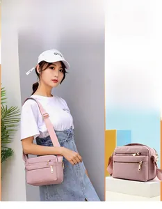 Detail view of pink waterproof nylon crossbody bag with multi-layer zipper pockets