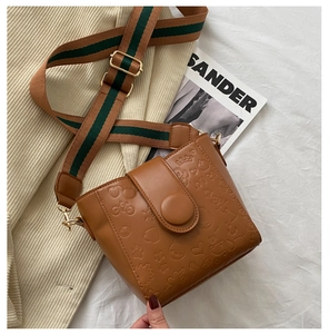Close-up of brown faux leather bucket bag with embossed cartoon patterns and stripe strap