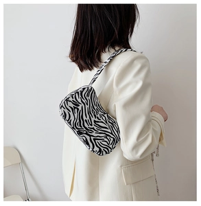 Detailed view of fashionable zebra print baguette bag worn as a shoulder underarm bag