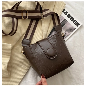 Close-up of dark brown bucket bag with lion and heart embossing and wide strap