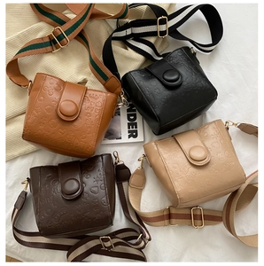 Detail view of four embossed leather crossbody bags with wide striped shoulder straps