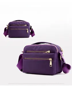 Detail of the purple nylon shoulder bag showing gold zippers and durable fabric texture