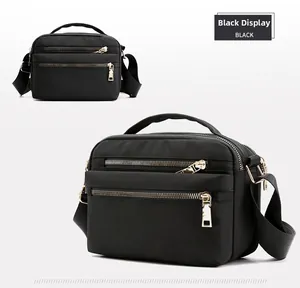 Close-up of black waterproof nylon crossbody bag with dual metal zippers and wide strap