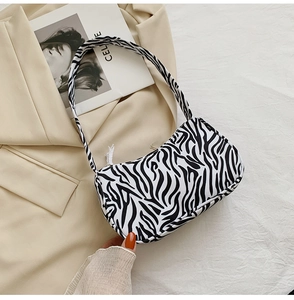 Detail shot of zebra print baguette bag on beige blazer with fashion magazine backdrop