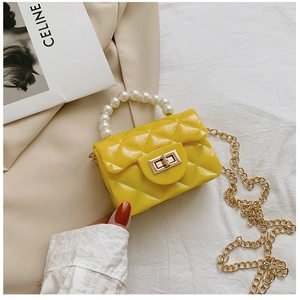 Close-up of bright yellow quilted jelly handbag with pearl handle and golden chain strap