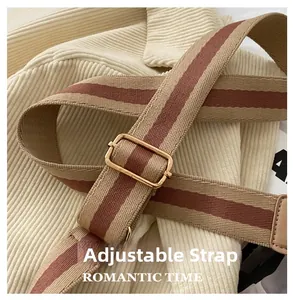 Close-up of adjustable striped canvas shoulder strap with high-quality gold metal buckle