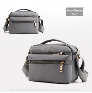 Detailed view of gray waterproof crossbody bag with multi-layer zippers and gold hardware