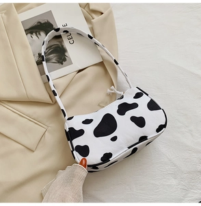 Detail of cow print armpit bag in crescent shape with black and white spot texture
