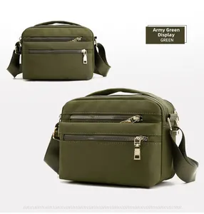 Detail view of military green waterproof nylon crossbody bag with golden zippers