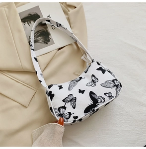 Close-up of white tote bag with black butterfly prints on faux leather material