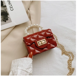 Detail of red quilted mini bag featuring pearl handle and golden chain strap