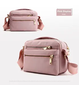 Detail view of pink nylon crossbody bag with three zipper compartments and gold hardware