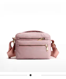 Detailed view of pink nylon shoulder bag with multi-zipper pockets and golden hardware