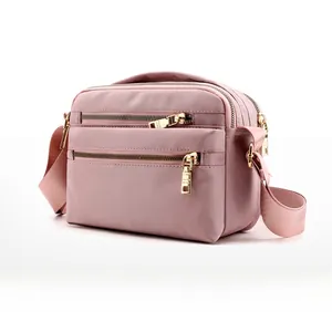Side view of pink water-resistant nylon crossbody bag featuring gold zippers and multi-layers