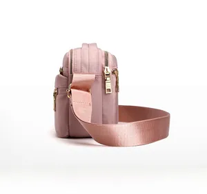 Side view of pink water-resistant crossbody bag featuring multi-layer zipper pockets