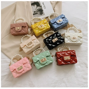 Macro shot of colorful mini jelly handbags with diamond quilt pattern and pearl handle detail