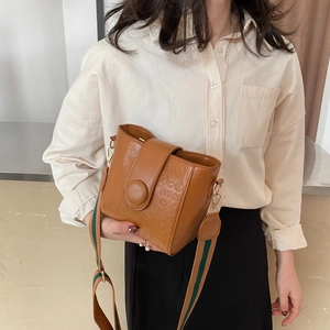 Brown vintage bucket bag with embossed heart patterns and a wide fabric shoulder strap
