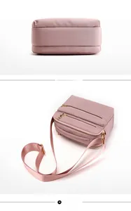 Detail showing pink water-resistant crossbody bag bottom and structure with gold zippers