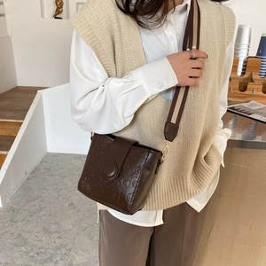 Vintage brown embossed bucket bag with adjustable wide strap shown in stylish daily outfit