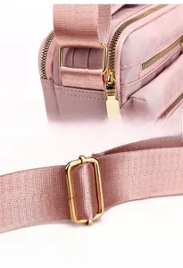 Detail of pink nylon bag featuring shiny gold zippers and adjustable strap fasteners
