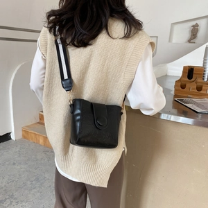 Classic black bucket bag with embossed texture and wide black white striped strap