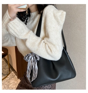 Close-up of black matte leather shoulder bag with a stylish zebra print silk scarf detail